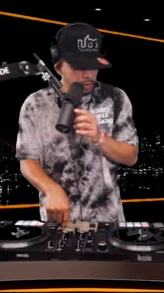 Bboy Wicket on the mic behind turntables during a live DJ set