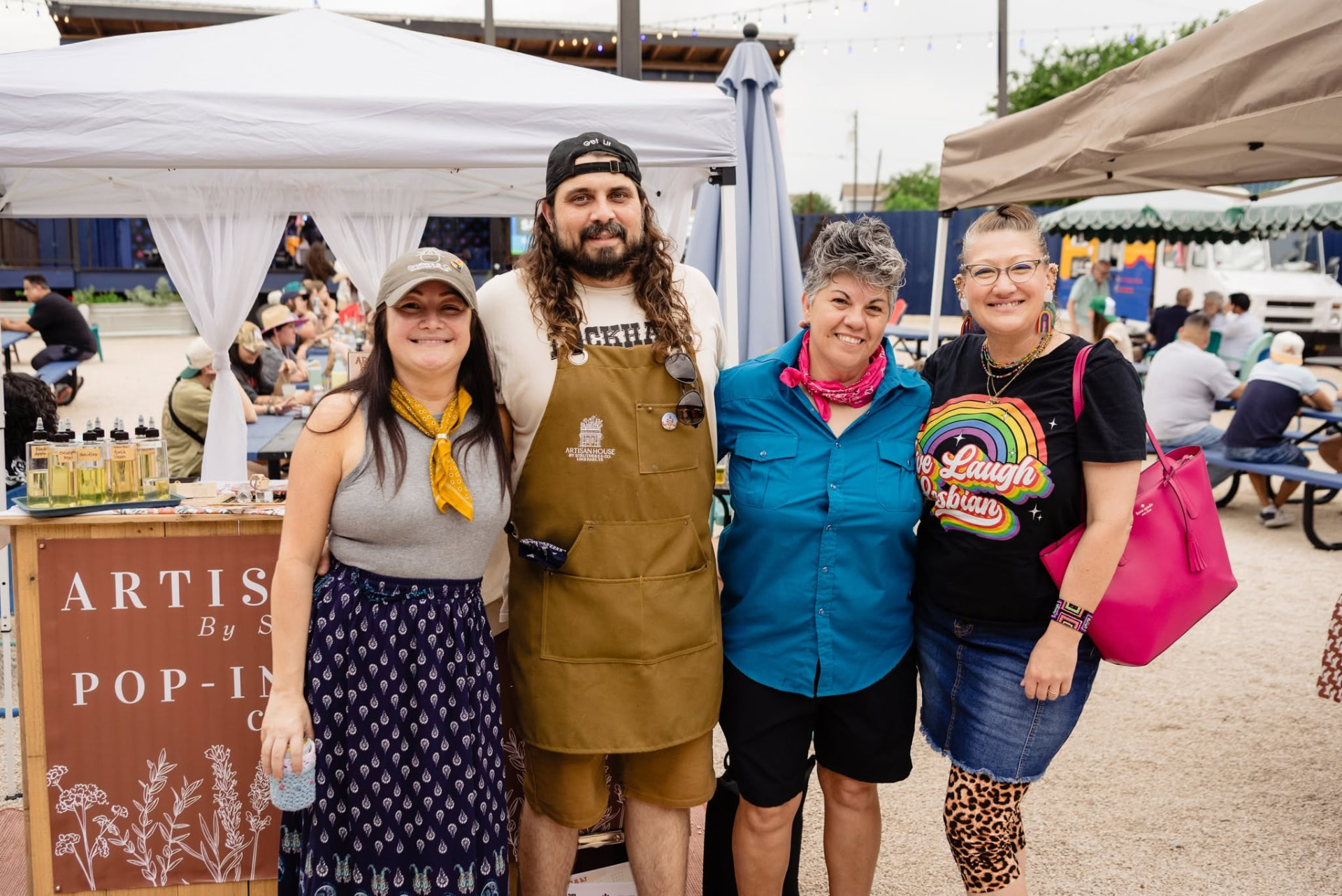 Four marketplace vendors posing together in front of their Artisan House booth