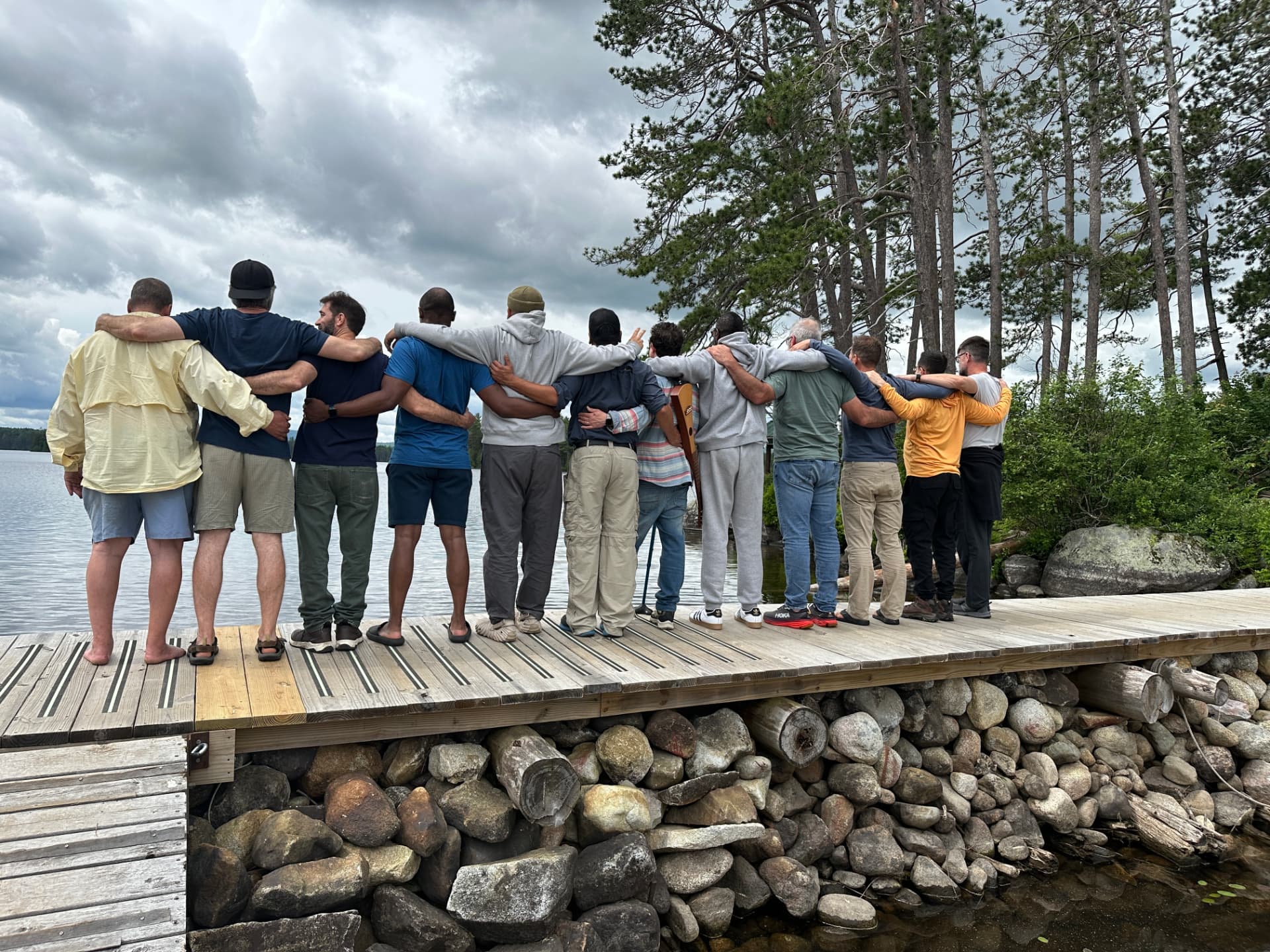 The dads standing arm in arm on a lakeside dock in northern Maine, from The Dads