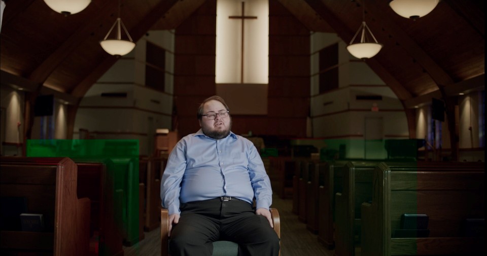 A member of the Austin Gay Men's Chorus seated in a church sanctuary, from This is Texas