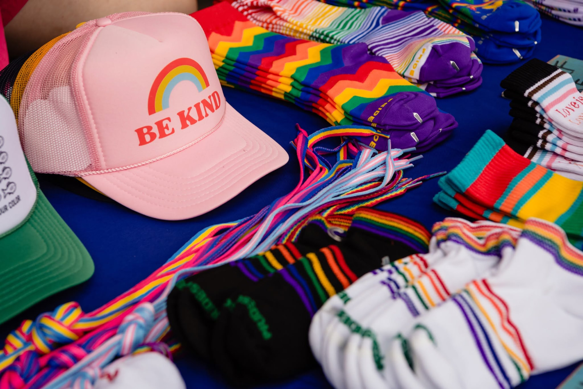 Pride socks, shoelaces and a pink 'Be Kind' trucker hat on a vendor table