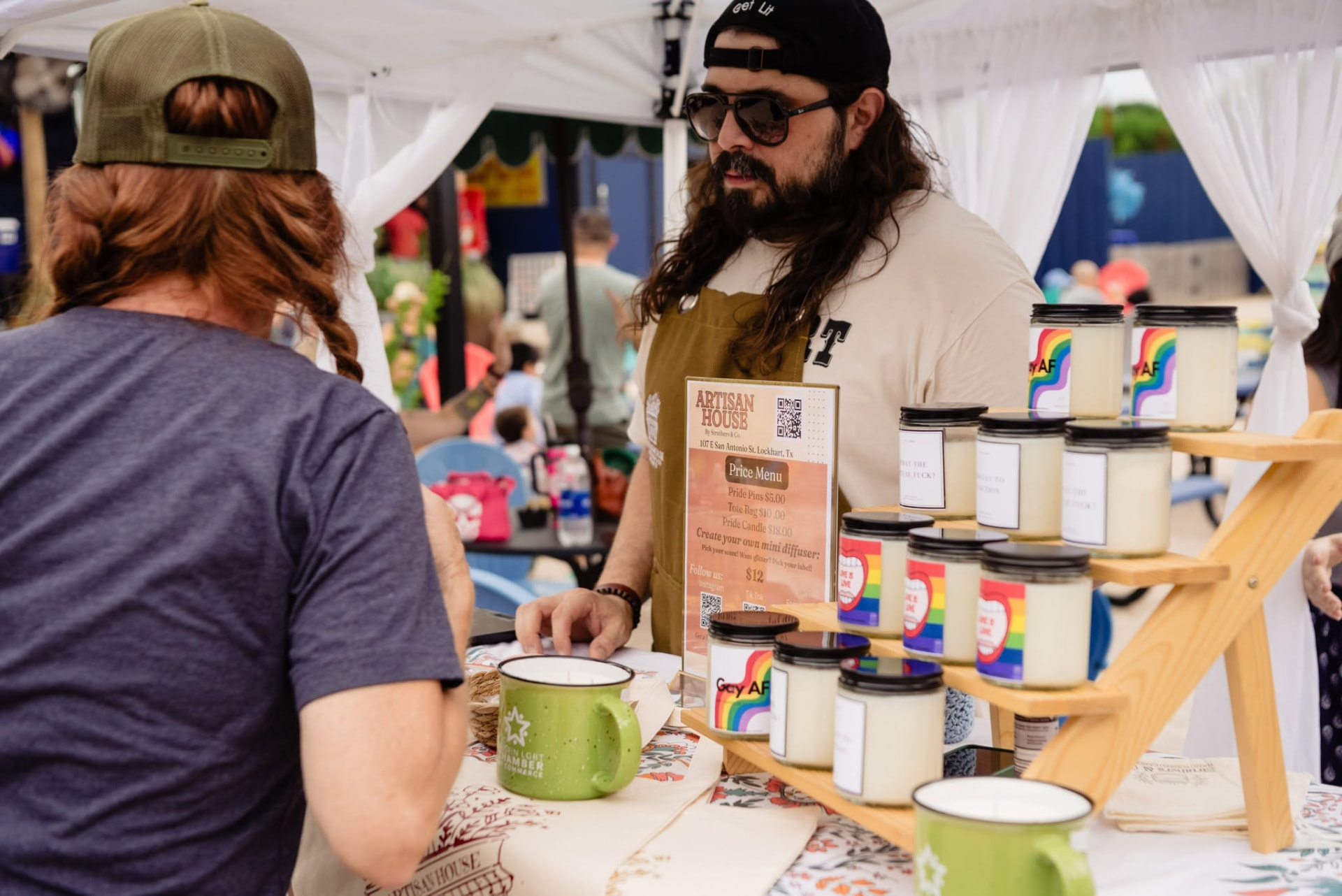A candlemaker behind a table of Pride candles at the Chamber's artisan marketplace
