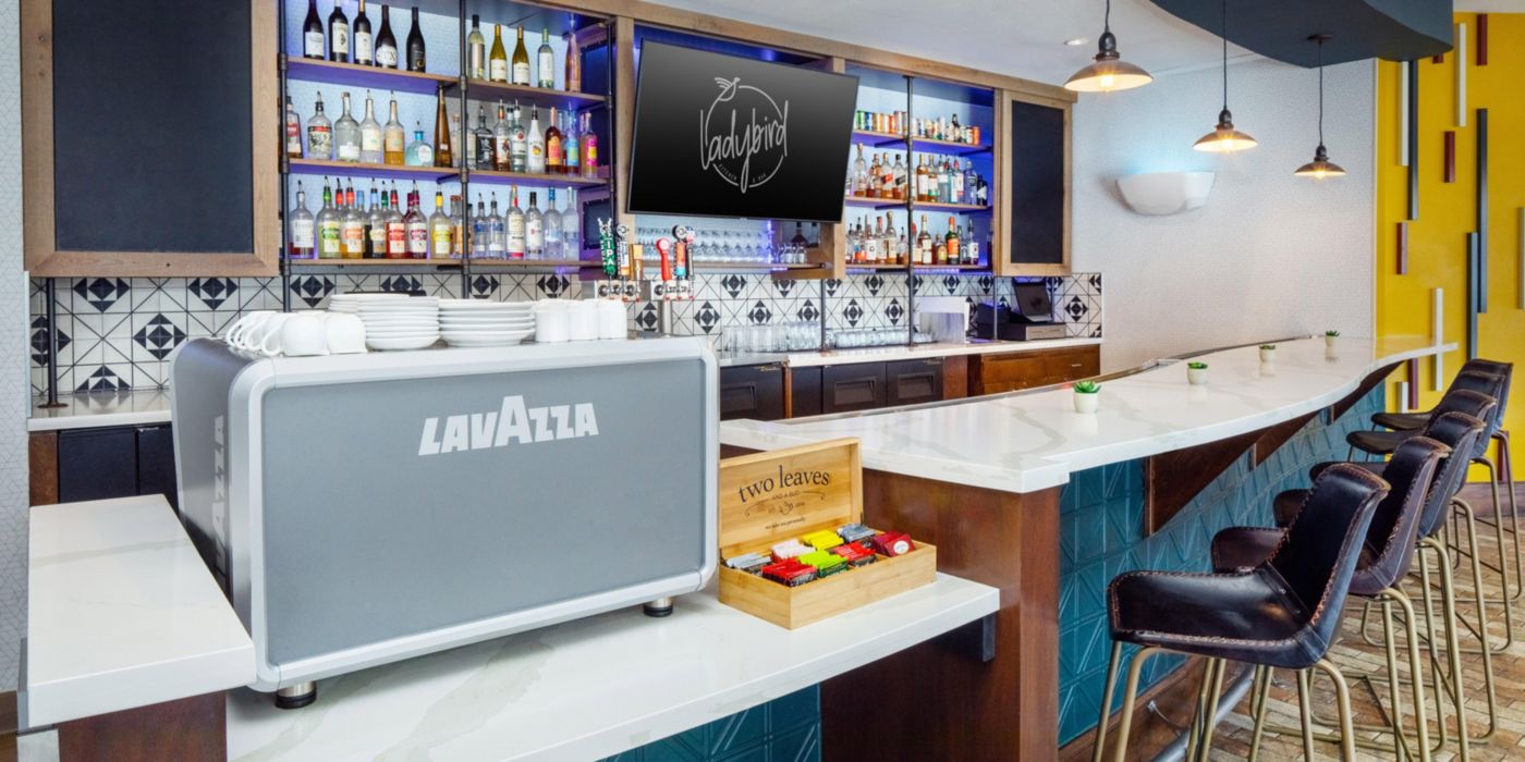 Backlit bar with an espresso machine at Urban Pour Social inside Hotel Indigo Austin