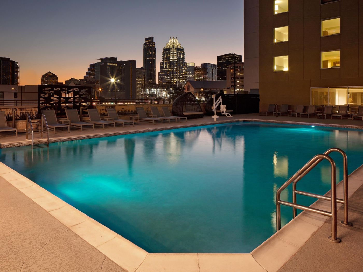Rooftop pool deck at Hotel Indigo Austin Downtown at dusk with the downtown Austin skyline behind it