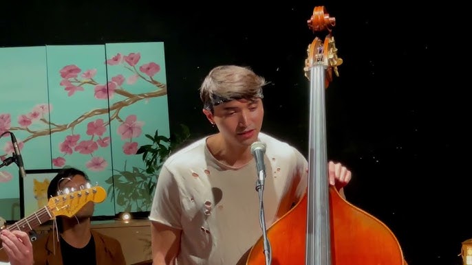 Maru Haru frontman James Tabata singing into a microphone while playing upright bass