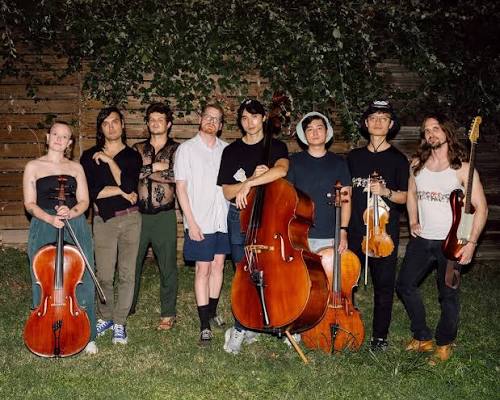 Maru Haru standing outdoors at night with cello, upright bass, violins and bass guitar